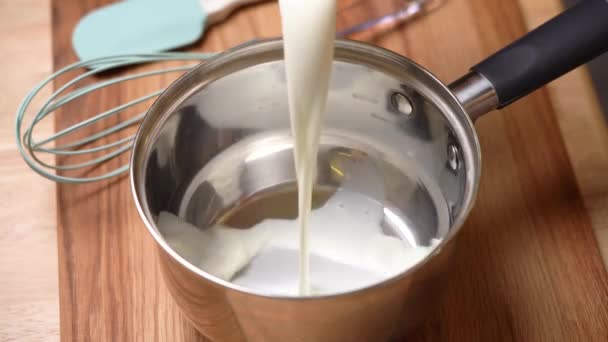 牛奶倒入站在切菜板上的金属锅里 — 图库视频影像