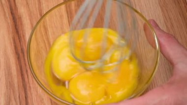 Tavuk yumurtalarının sarısı çırpılmış ve masanın üzerinde cam bir kase ile çırpılmış.. 