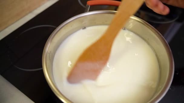 牛奶在电炉上沸腾 用木铲搅拌 — 图库视频影像