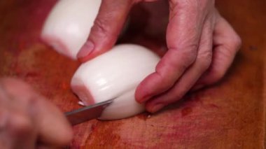 Yakından çekilen videoda hala beyaz bir soğanın tahta bir tahtada bıçakla dilimlendiği görülüyor. Yemek pişirme ve bıçak kullanma becerileri için harika..