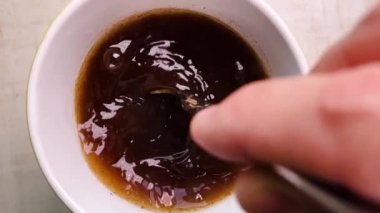 Bir fincanda kahverengi sıvıyı karıştıran bir elin yakın çekimi hareketi yakalıyor ve dalgalanmalar yaratıyor. İçeceğe hazırlık, dinamik eylem ve aşçılık süreci kavramları için idealdir 