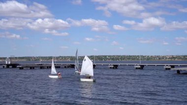Yelkenliler, 3 Temmuz 2025 'te, güneşli bir yaz gökyüzünün altında, Ukrayna' nın Mykolaiv kentindeki bir köprünün yakınındaki Güney Böcek nehri boyunca hareket ederler.. 