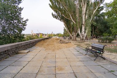 19 Temmuz 2025 'te, Ukrayna' nın Mykolaiv kentinde, nehir kenarındaki patikanın bir kısmı kum bloklarıyla dolu bir siper onarımlar devam ederken. 