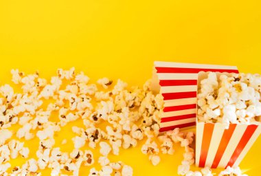 Sarı zemin üzerinde patlamış mısır ve dekoratif balkabağı olan kırmızı ve beyaz çizgili kutular. Eğlence konsepti. Patlamış mısırlı Autumn Movie gecesi. Sonbahar Sinema teması.