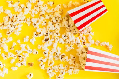 Sarı zemin üzerinde patlamış mısır ve dekoratif balkabağı olan kırmızı ve beyaz çizgili kutular. Eğlence konsepti. Patlamış mısırlı Autumn Movie gecesi. Sonbahar Sinema teması.