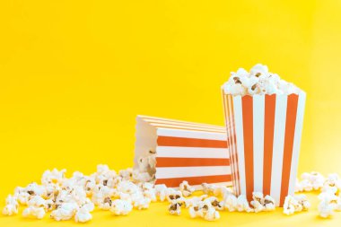 Sarı zemin üzerinde patlamış mısır ve dekoratif balkabağı olan kırmızı ve beyaz çizgili kutular. Eğlence konsepti. Patlamış mısırlı Autumn Movie gecesi. Sonbahar Sinema teması.