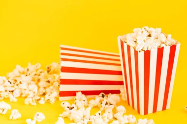 Sarı zemin üzerinde patlamış mısır ve dekoratif balkabağı olan kırmızı ve beyaz çizgili kutular. Eğlence konsepti. Patlamış mısırlı Autumn Movie gecesi. Sonbahar Sinema teması.