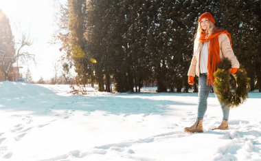 Güzel genç bir kadın Noel çelengini güneşli bir gün yaptı. Noel ve yeni yıl indirimi konsepti..