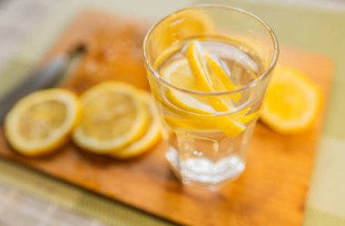 Limon dilimleri ve bir bardak su yakın. Sağlıklı yiyecek veya içecek konsepti.