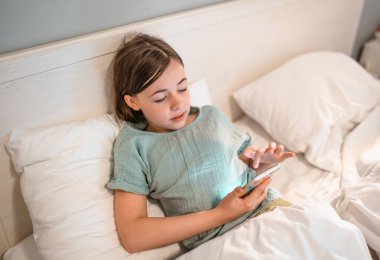 Yatmadan önce akıllı telefonu olan çocuk.