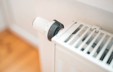 Hand regulates the heat in the house on the radiator handle.	