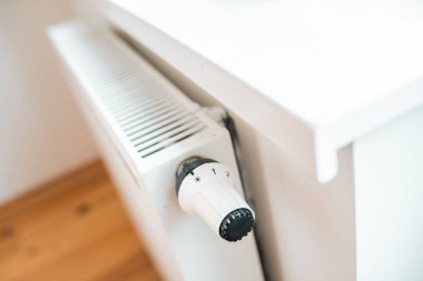 Hand regulates the heat in the house on the radiator handle.	