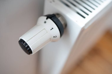 Hand regulates the heat in the house on the radiator handle.	