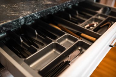 Organize kaşıklar, çatallar ve bıçaklarla dolu modern mutfak çekmecesi. Mutfak uzay organizasyonu.