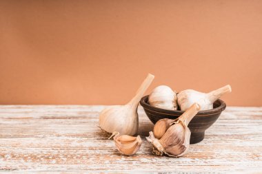 Taklit alanı olan ahşap bir masada sarımsak ampulleri. Beslenme kavramı.