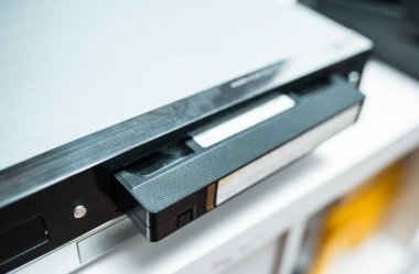 Elinde bir video kaset olan bir elin yakınına. Bir oynatıcıda Retro vhs kaseti..