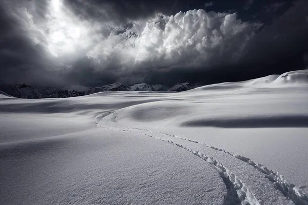 a snow covered field with a sky filled with clouds and a trail in the snow leading to a mountain..