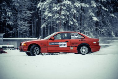 12-12-2022 Riga, Letonya. Ormanın yakınına park etmiş kırmızı bir araba. Üzerinde kar arabası yazan bir tabela var.. .