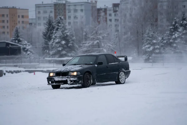 stock image 12-12-2022 Riga, Latvia a car parked in the snow in front of a building with a red light on it's headlight. .