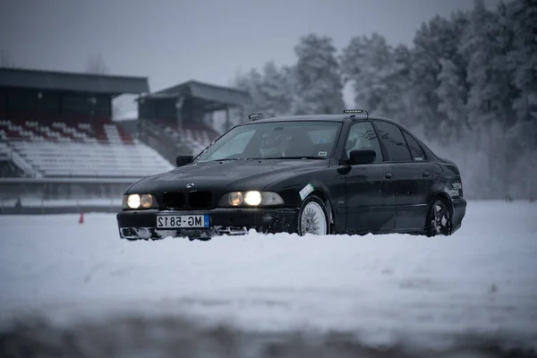 ラトビア リガ2012年12月12日2022年12月12日スタジアム近くの雪の中に黒い車が停まっている — ストック写真