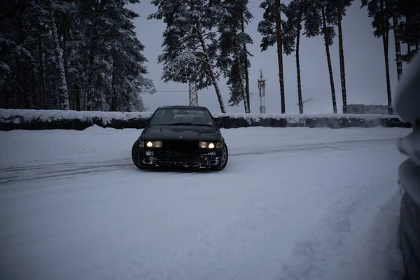 ラトビア リガ2012年12月12日2022年12月12日ラトビア リガ雪の中の雪道を走る車で 背後にはヘッドライトや木 雪の中に立つ人 — ストック写真