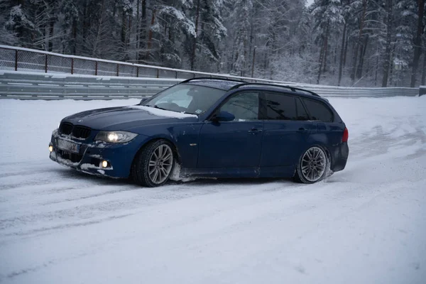 2012年12月12日から2022年までの間 ラトビアのリガには青い車が柵や木の近くの雪の中に停まっています — ストック写真