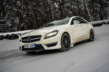 12-12-2022 Riga, Letonya. Beyaz bir Mercedes Cla ormanda karlı bir yolda ilerliyor. Arka planda ağaçlar ve yerde kar var.. .