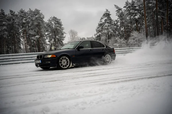 2012年12月12日 2022年リガ ラトビア木々の森とその上に雪のフェンスの横に雪に覆われた道路を運転する黒い車 — ストック写真