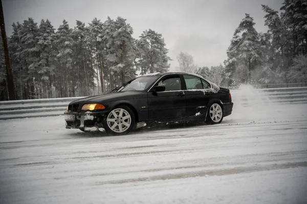 2012年12月12日 2022年リガ ラトビア木々の横に雪に覆われた道路を運転する黒い車とその上に雪のフェンスと地面に雪のほこり — ストック写真