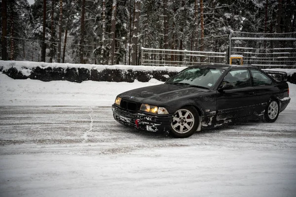2012年12月12日 2022年リガ ラトビア地面に雪と前景のフェンスを背景にフェンスや木の近くの雪の中に駐車車 — ストック写真