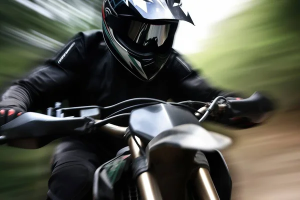 a man riding a motorcycle down a street next to a lush green forest filled with trees on a lush green field covered in leaves and grass.