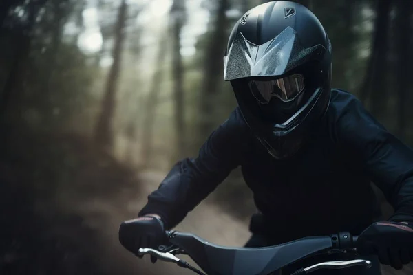 a person wearing a helmet and riding a motorcycle in the woods on a trail in the woods with trees in the background and a trail in the foreground.
