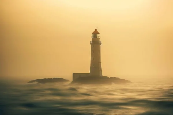 a light house in the middle of the ocean with a foggy sky behind it and a small island in the middle of the ocean.