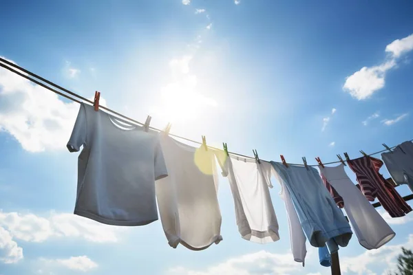 a line of clothes hanging on a clothes line with the sun shining in the sky behind them and a line of clothes hanging on a clothes line.