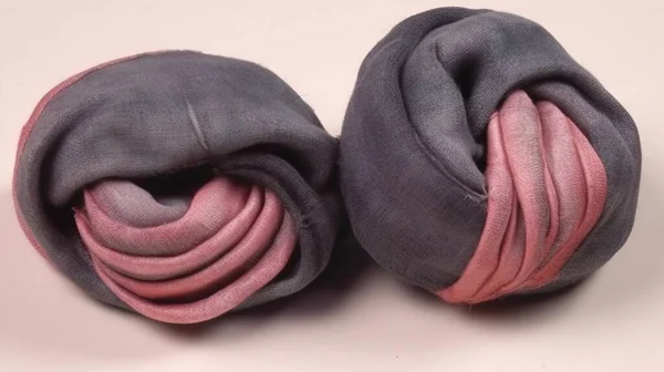 a pair of gray and pink scarves on a white surface with a pink stripe down the middle of the scarves and a pink stripe down the middle of the scarves.