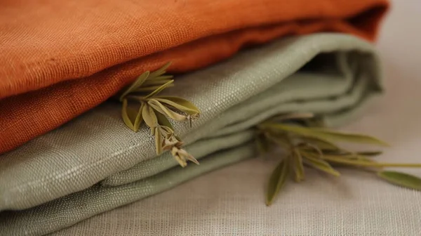 a close up of a folded cloth with a plant on top of one of the folded cloths on the other side of the folded cloth.