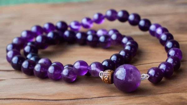 a purple beaded bracelet on a wooden surface with a gold clasp.