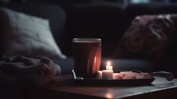 a candle and a glass on a table in a dark room.