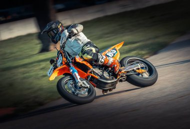  Arka planda çim olan bir pistte motosiklet süren biri. üretici ai