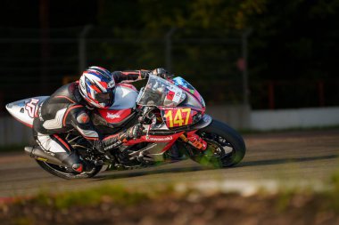  Arka planda ağaçlar olan bir pistte motosiklet süren biri. üretici ai