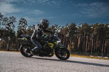  Ormanın yanındaki caddede motosiklet süren bir adam. üretici ai