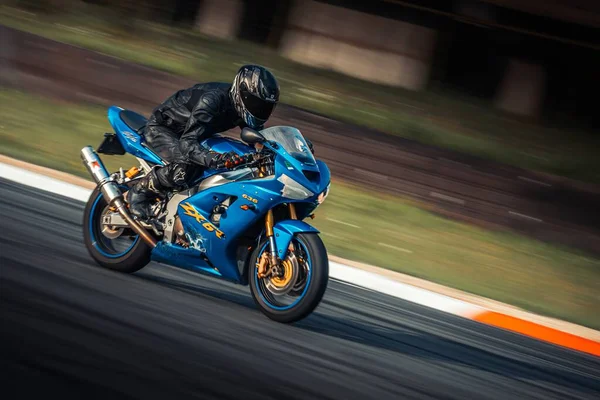 バックグラウンドでレースコースで青いオートバイに乗っている人 ジェネレーティブ エイブ — ストック写真