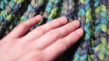 Kadın eli renkli yün bir şapkaya ya da kalın bir kazağa dokunuyor. 4k görüntü.