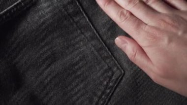 Girl touching a smooth black jeans, checking the quality of fabric in a clothing store or textile factory. High quality footage.