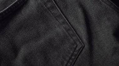 Woman touching black cotton jeans fabric in a textiles shop. Closeup shot.