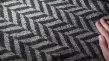 Girl touching patterned fabric, scarf or sweater or wool or acrylic in textiles shop. 4k shot.