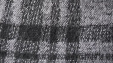 Close-up shot of checkered acrylic or wool fabric, womens sweater or scarf, monochrome palette. Slow pan shot.