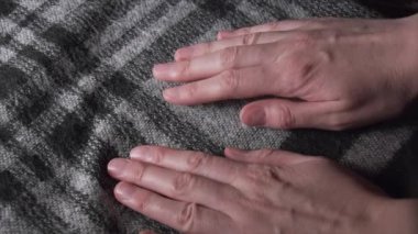 Close-up of womens hands dealing with acrylic or wooly checkered scarf in monochrome colors. Close up shot.