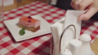 A person uses paper napkins while eating. A mans hand brings a napkin to him and takes it from napkin holder. Napkins in the italian restaurant on the table. 3840x2160p high quality footage.