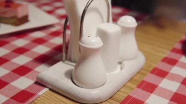 A person takes pepper shaker in a restaurant. A mans hand brings pepper to himself during his lunch or dinner. Close-up view footage.